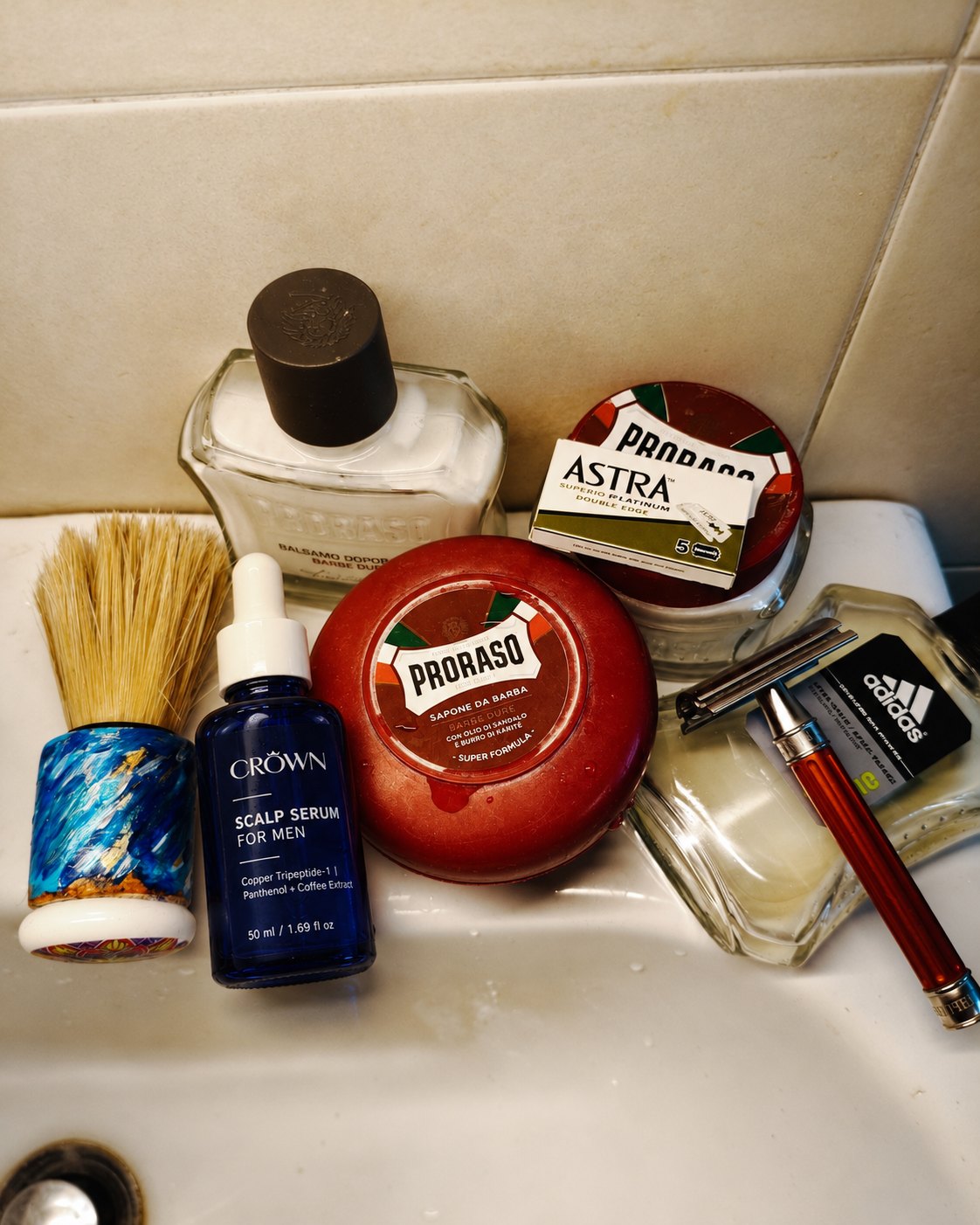 CROWN Scalp Serum on a bathroom sink next to a shaving brush and razor